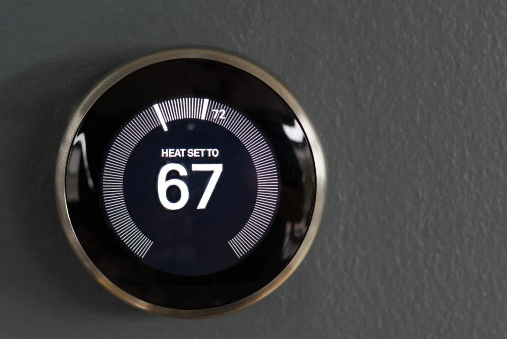 Wall-mounted smart thermostat displaying a heating setting